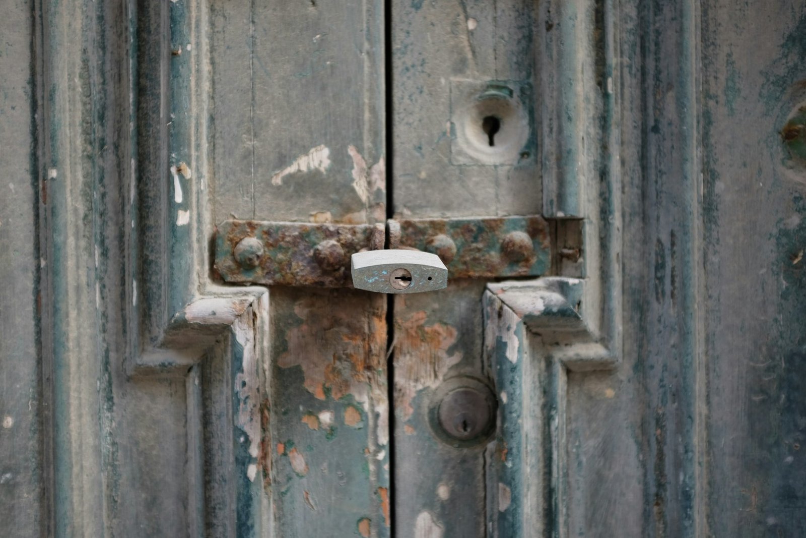 Padlock and latch on a weathered timber door